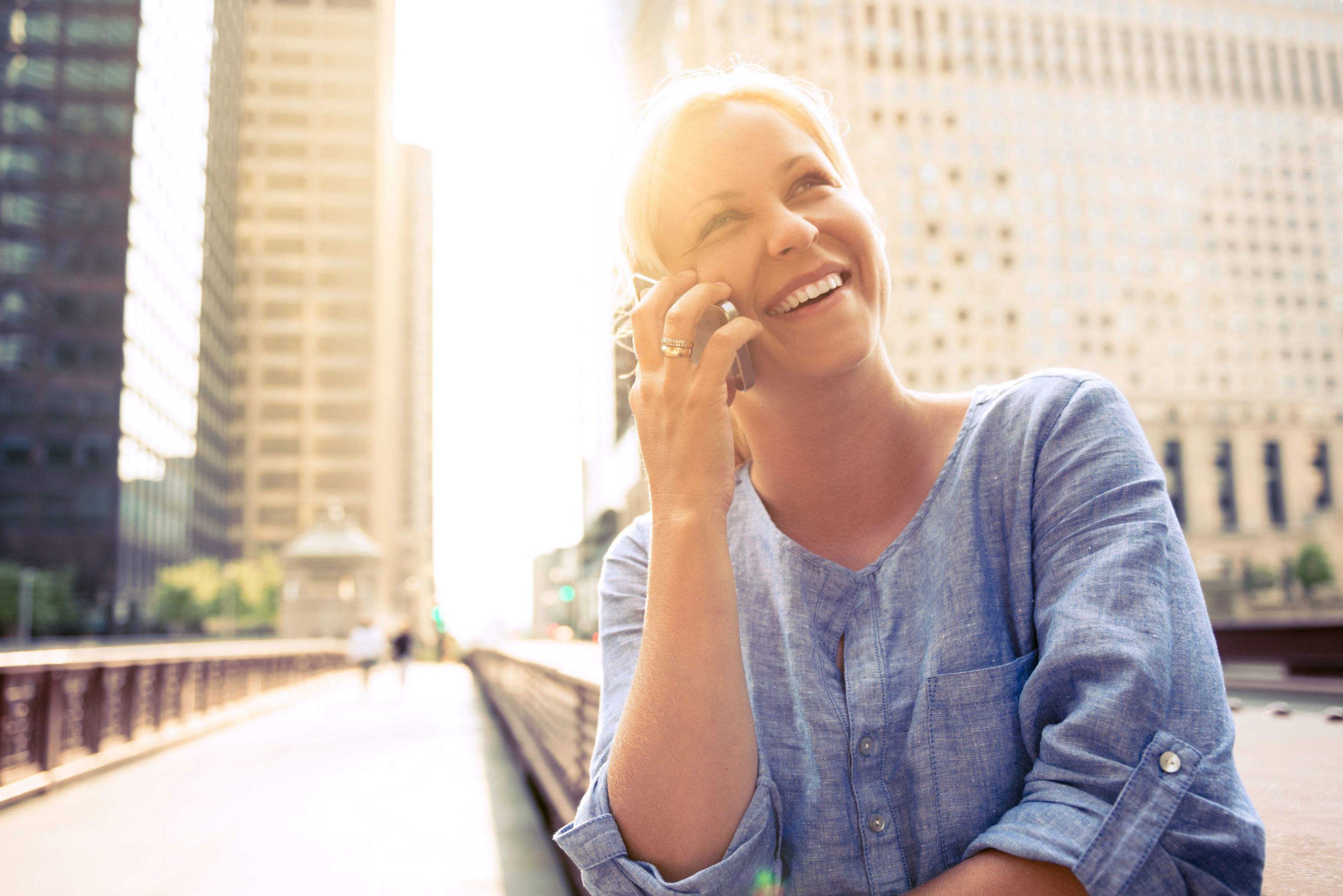 woman with beautiful teeth smiling and holding a phone to her ear