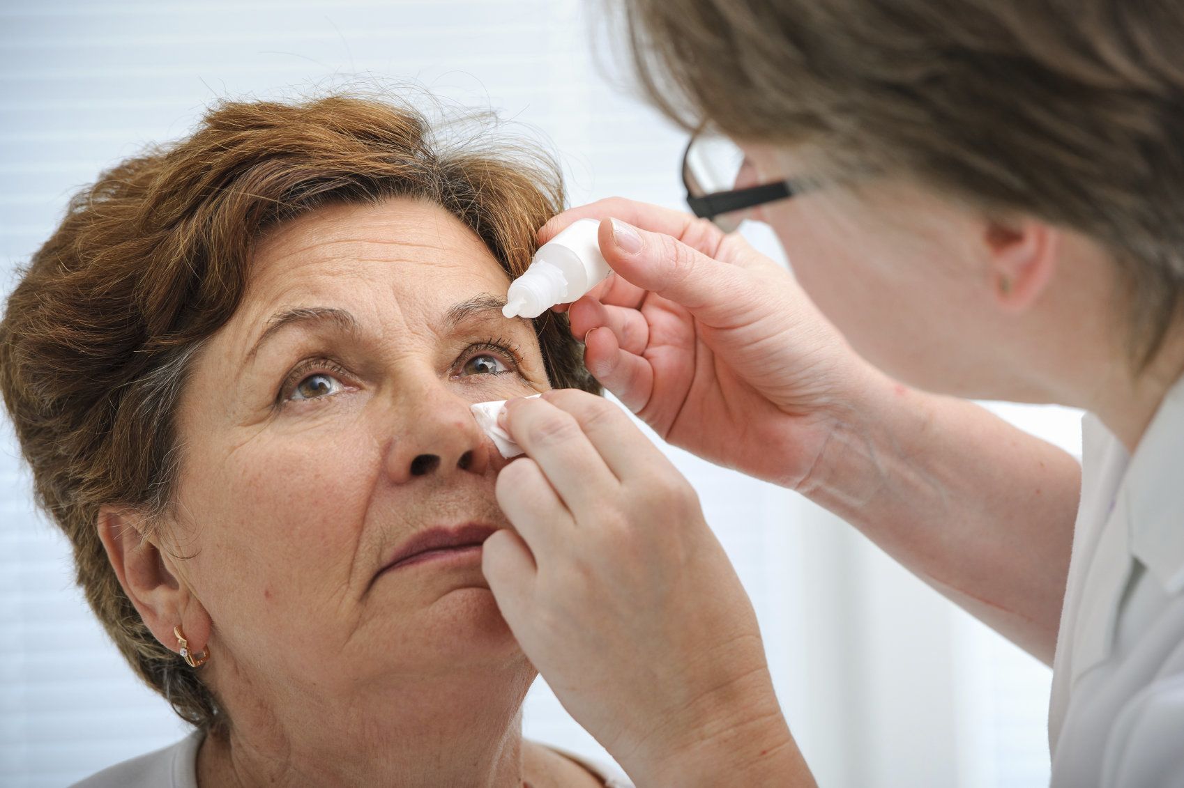 Doctor using eye drops on a patient