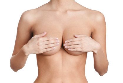 A hand holding a naked breast.