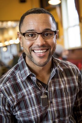 Casual, dark-haired young man in plaid shirt, in a home