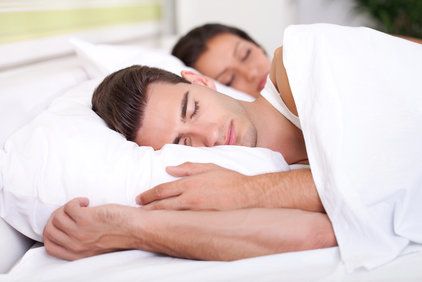 Couple sleeping in a bed with white sheets