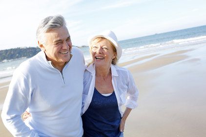 Laughing Caucasian couple walking arm-in-arm on the beach