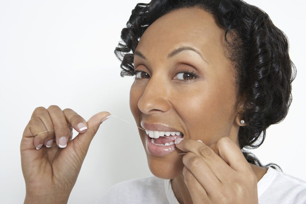 Woman with curly brown hair flossing