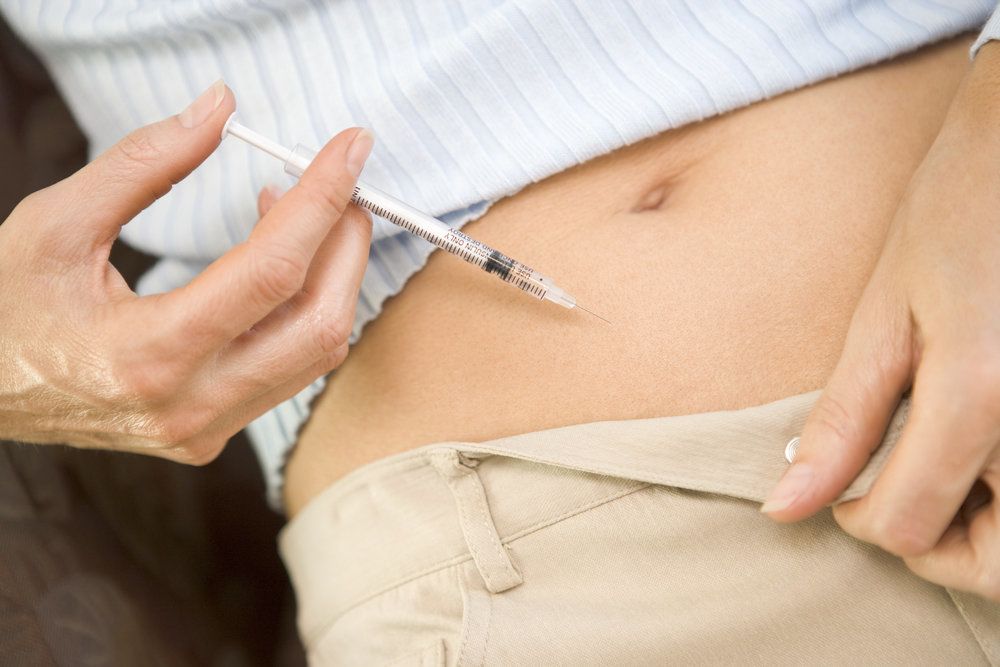 A woman giving herself an IVF trigger shot in her stomach