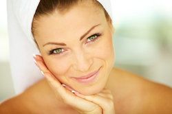 Beautiful smiling woman with hair wrapped in spa towel