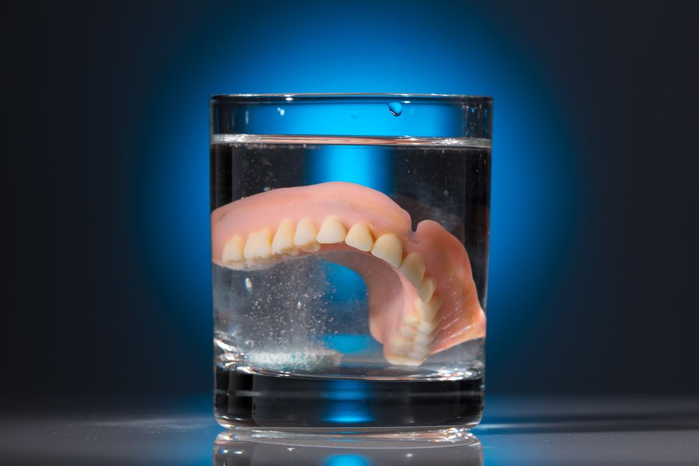 dentures in a glass of denture cleaner