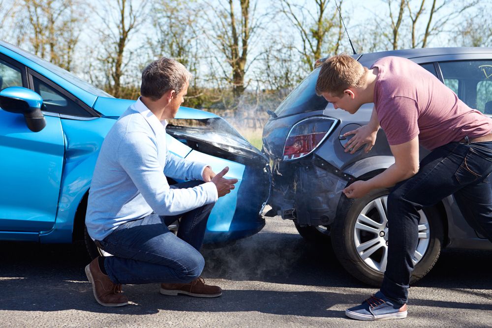 two men looking at their cars after an accident