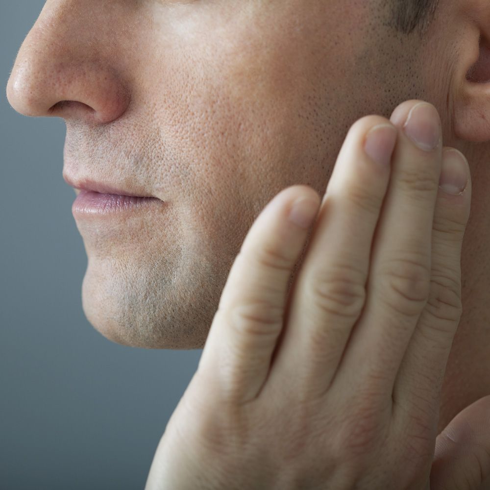 A man holding his hand to his jaw