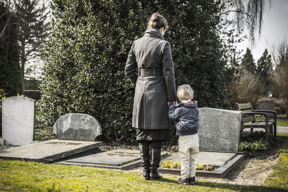 A mother and child visiting the grave of the deceased patriarch of the family, who died in a construction accident