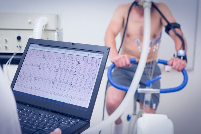 Diagnostic information on a computer screen with man riding an exercise bike in the background