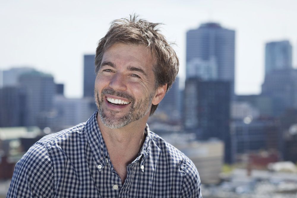 Photo of smiling man standing in front of a cityscape