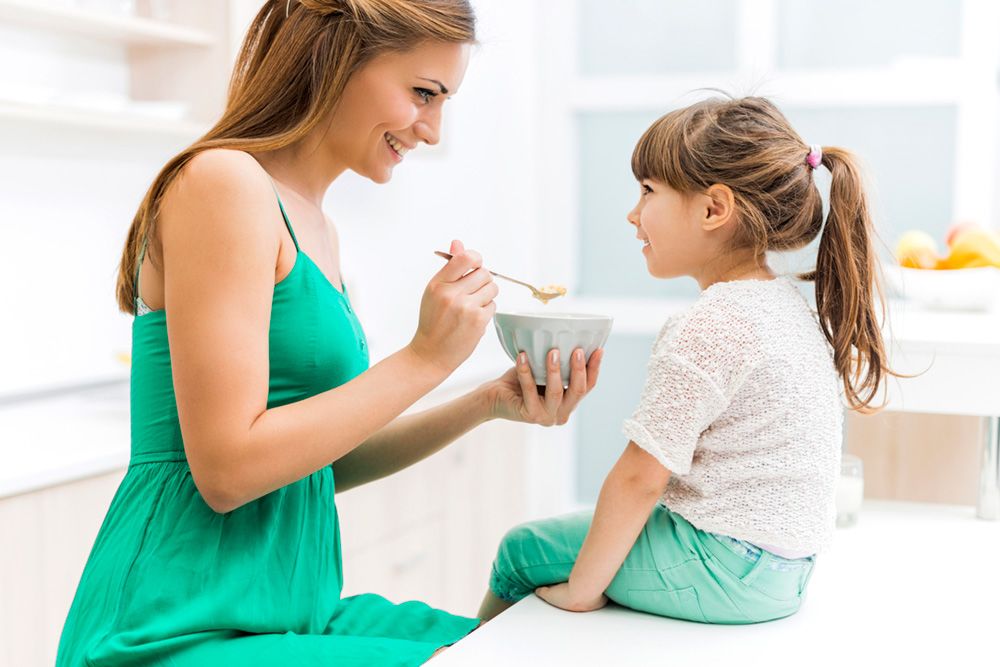 A mother feeding her young daughter.
