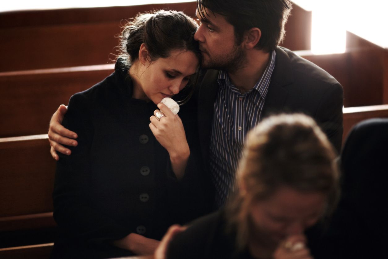 man consoling a woman at a funeral