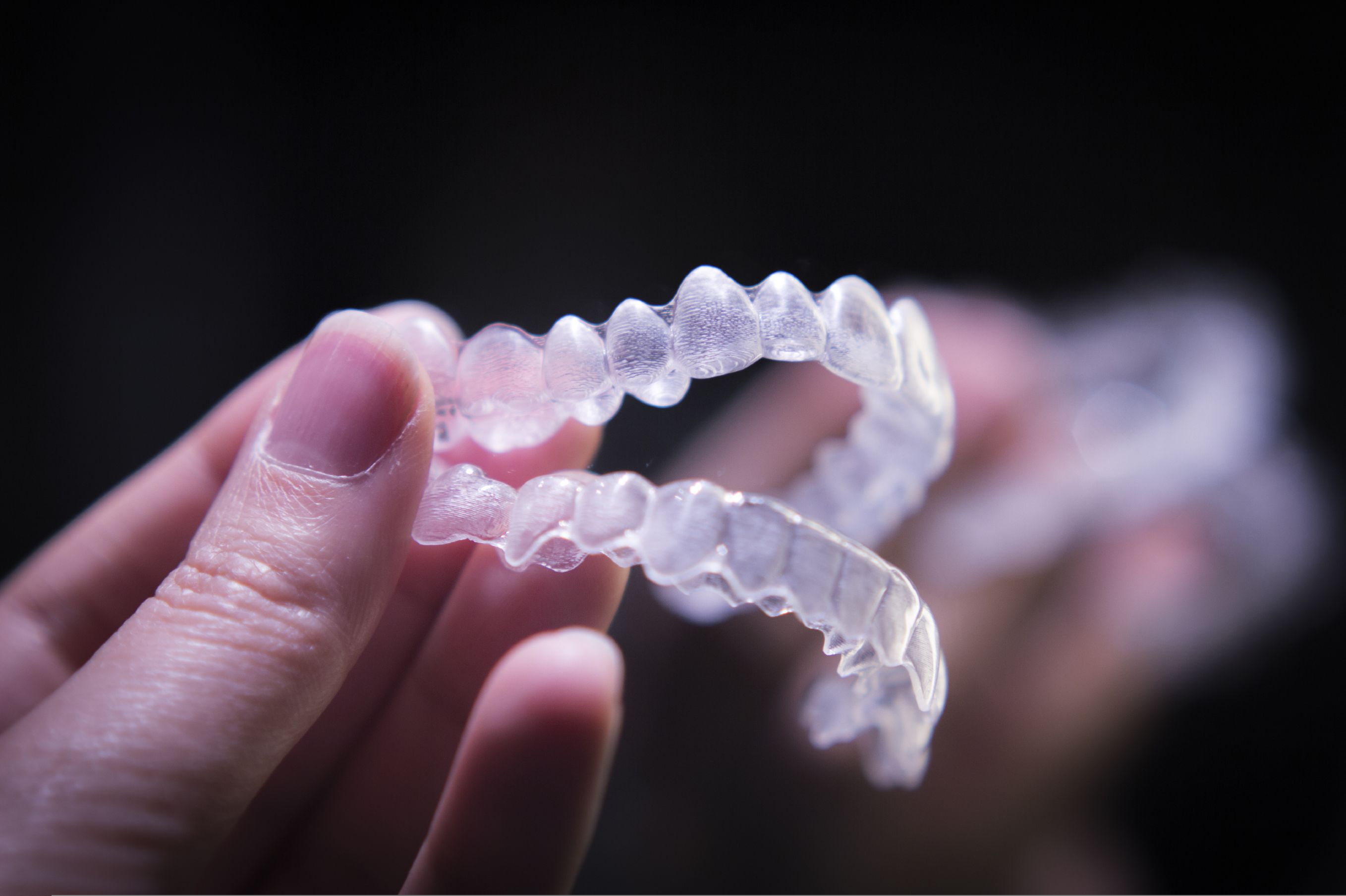 Closeup of hand holding top and bottom Invisalign trays