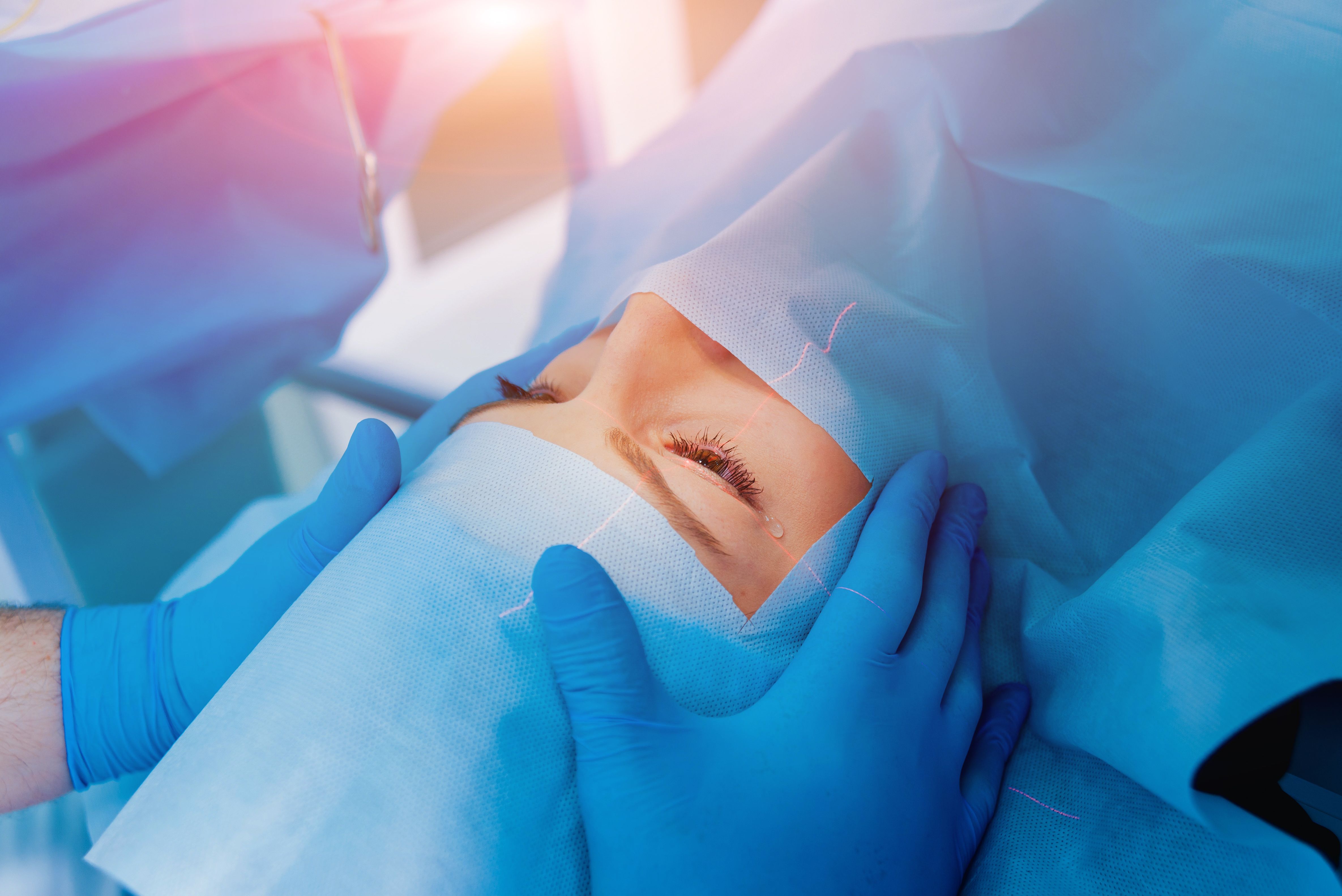 A woman reclines and sheds a single tear as she receives LASIK surgery