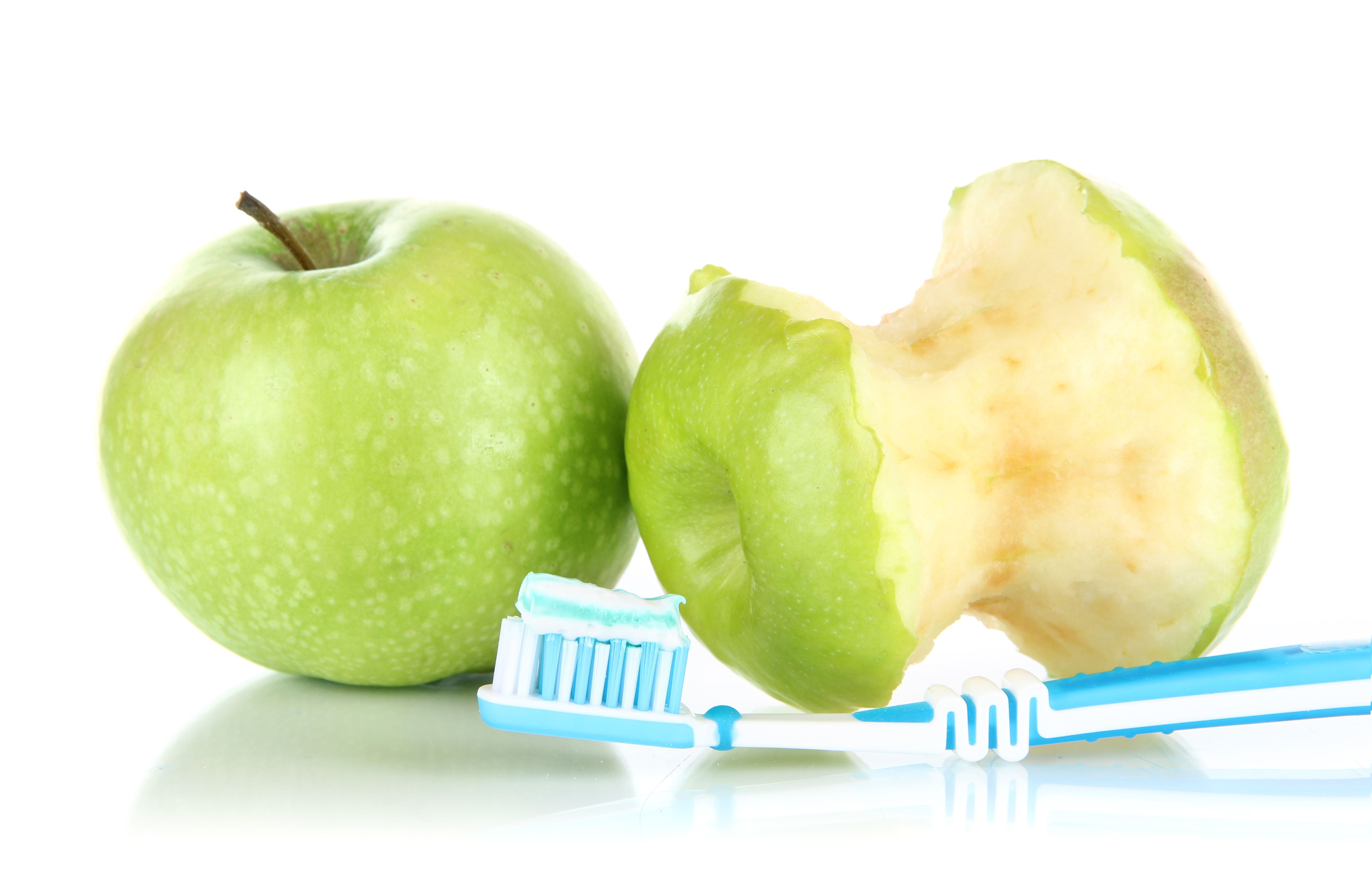 Two apples sit with a toothbrush in front 