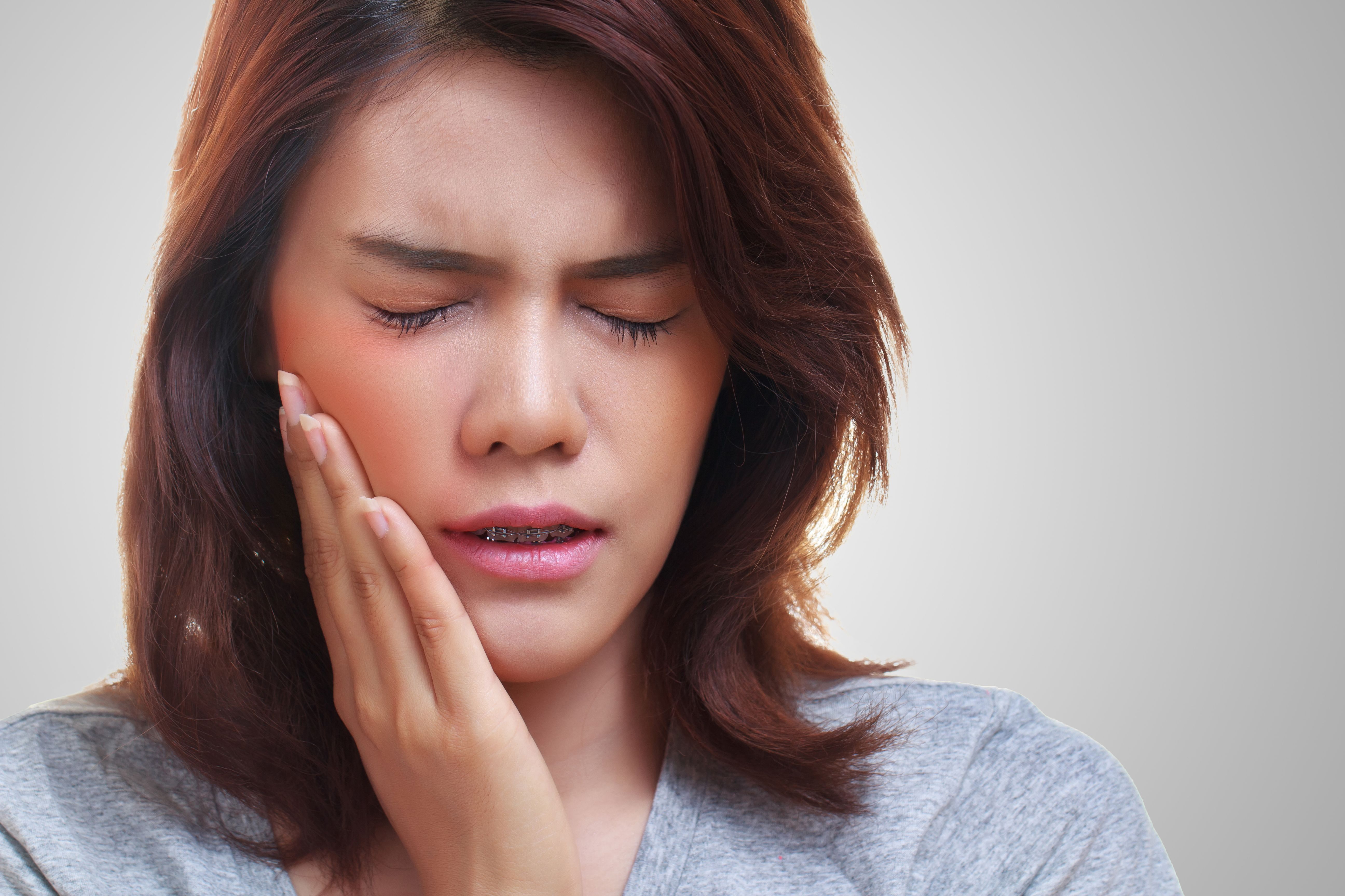 A woman holding her hand to her face in pain