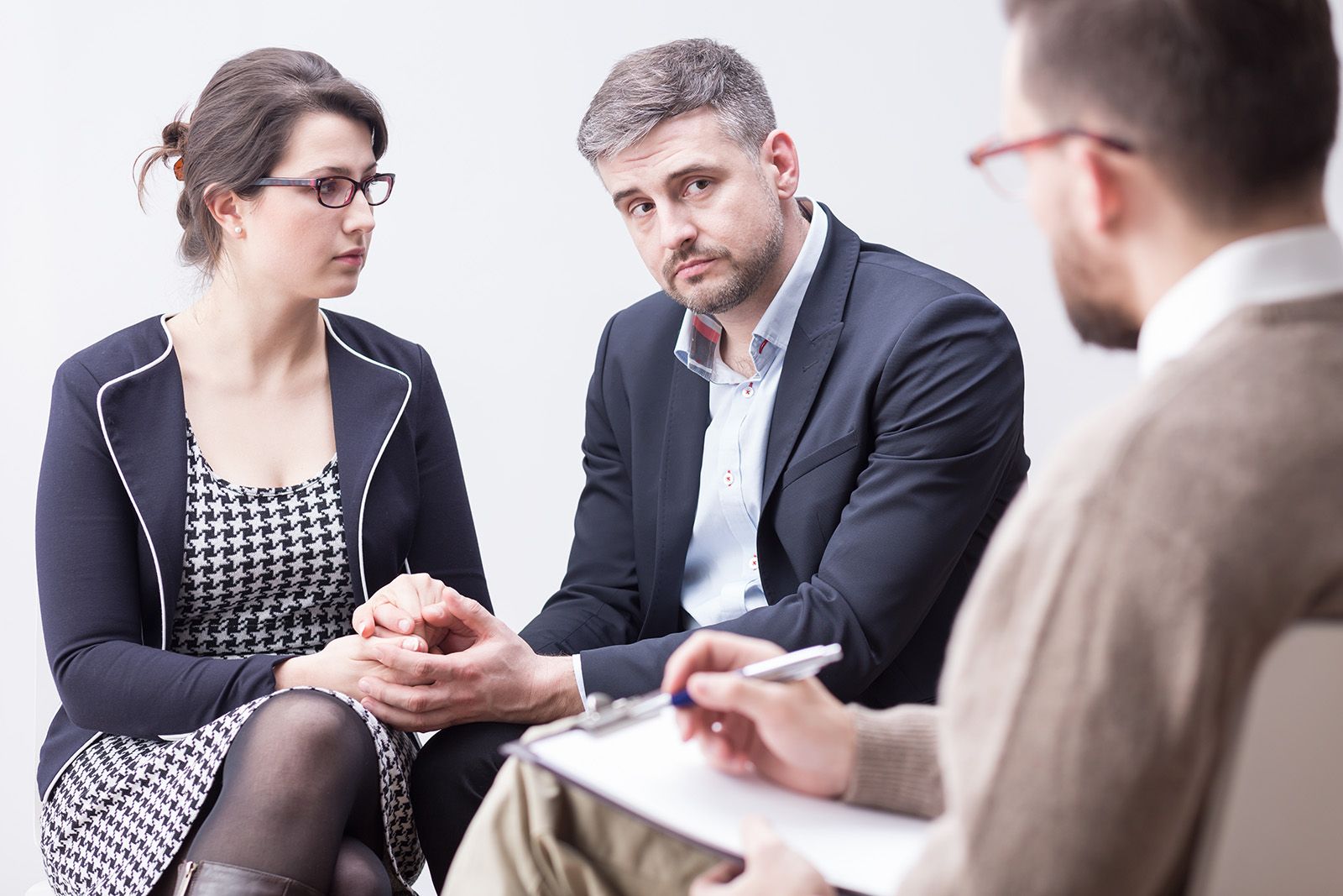 A man holding a notepad sitting with a couple