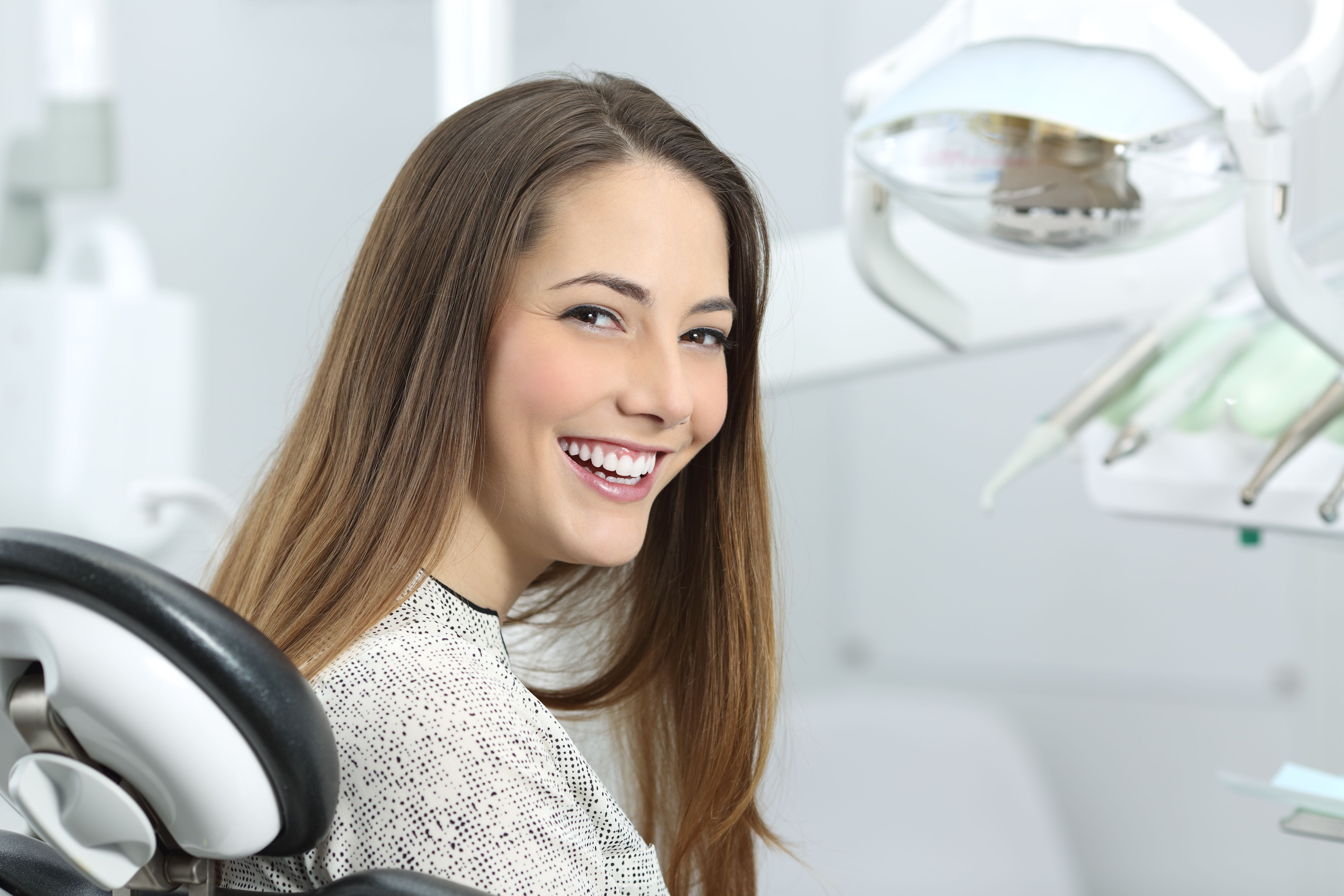 A young woman sitting in a dentist’s chair smiling