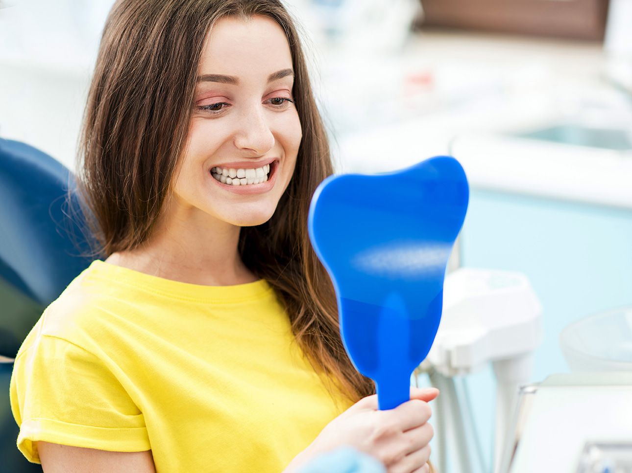 A woman looking at her straight teeth after treatment for a jutted tooth