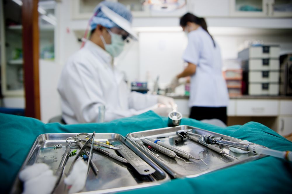 two trays with surgical tools and a surgeon in the background