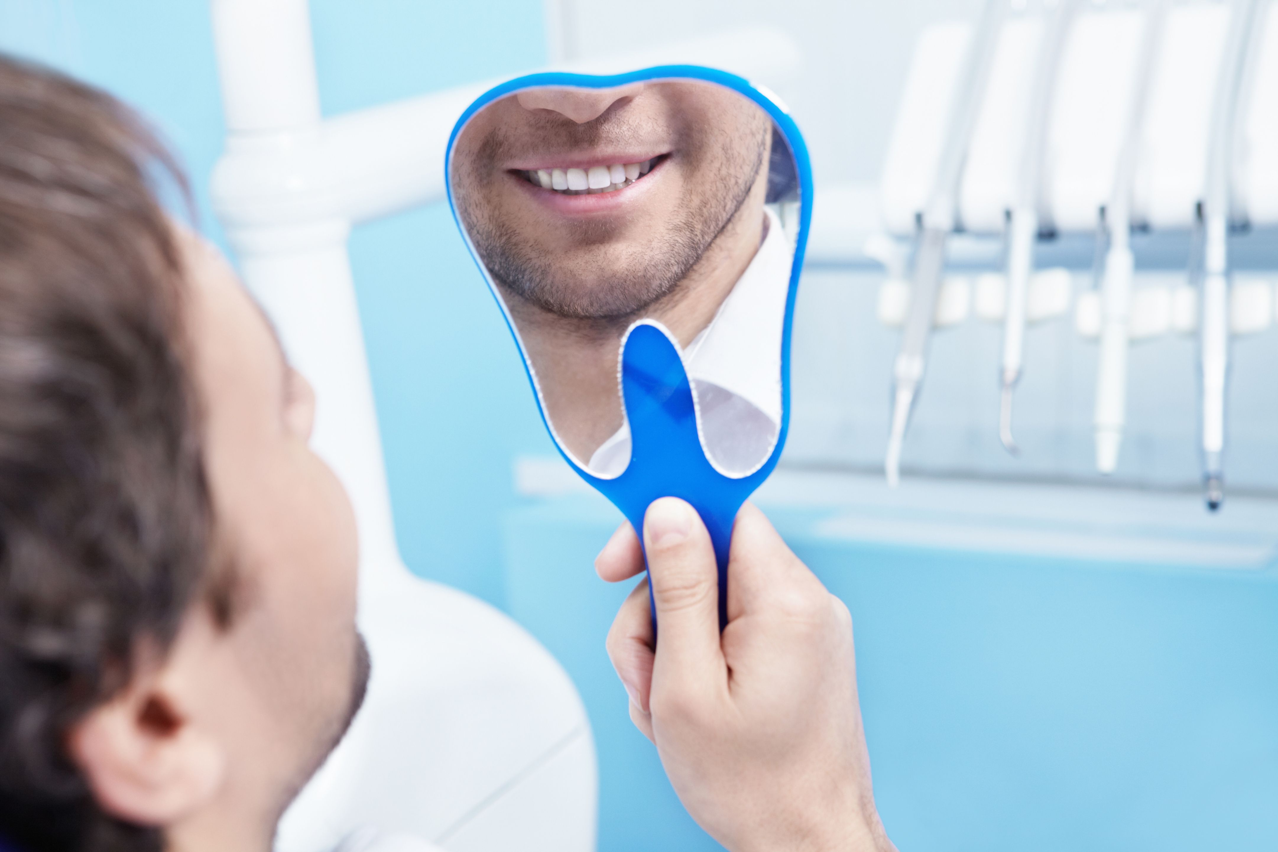 man smiling into a tooth-shaped mirror